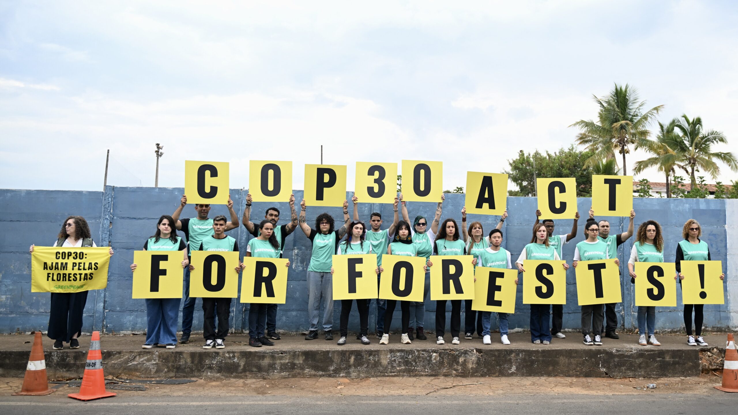 Members of Greenpeace hold sign demanding action to save the forests, outside of the Pre-COP30 opening ceremony, a preparatory meeting bringing together ministers responsible for climate negotiations, in Brasilia, Brasil, on October 13, 2025.