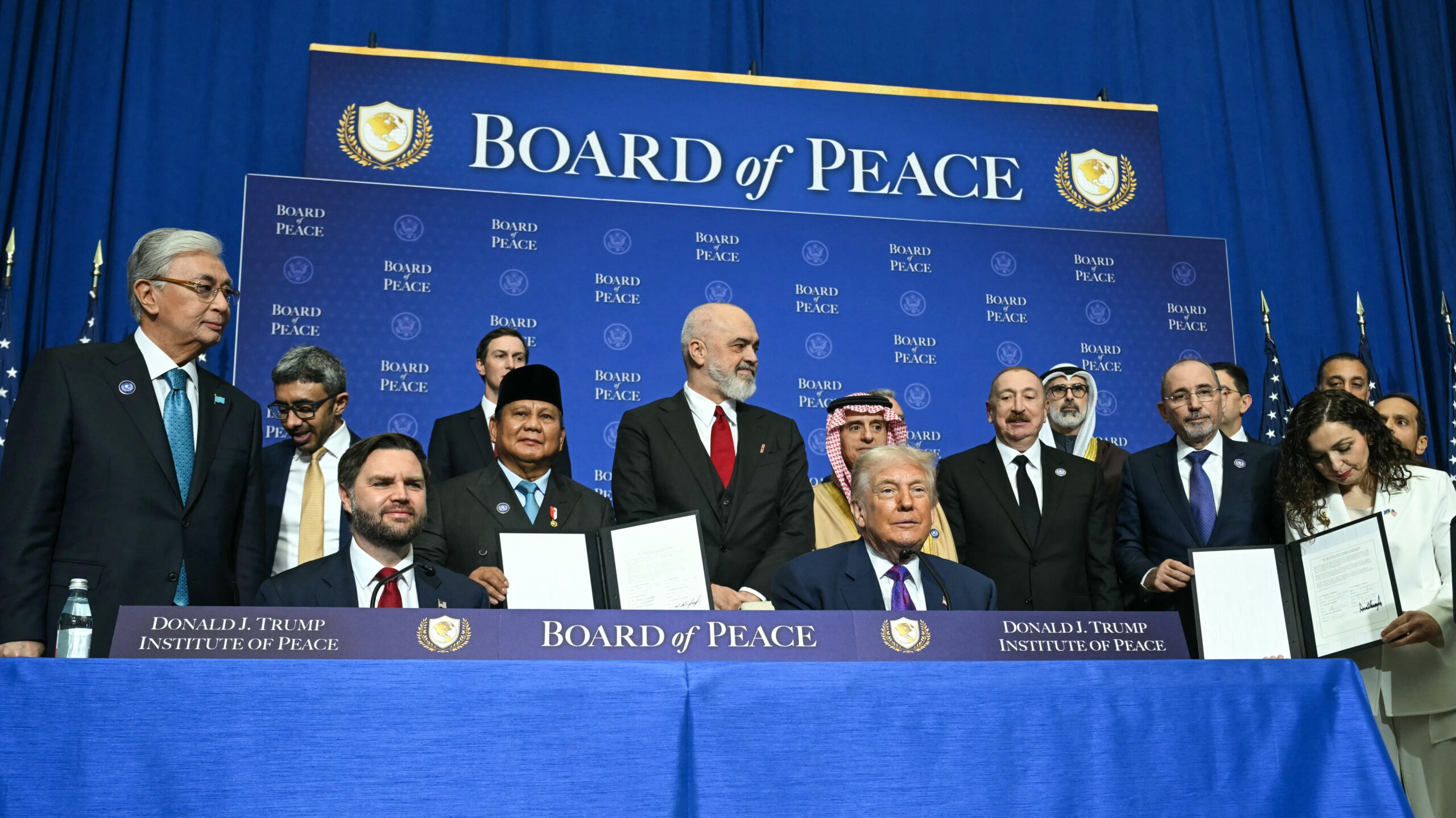 S President Donald Trump and US Vice President JD Vance sit together surrounded by members of the "Board of Peace" during a signing ceremony at the inaugural meeting of the "Board of Peace" at the US Institute of Peace in Washington, DC, on February 19, 2026.