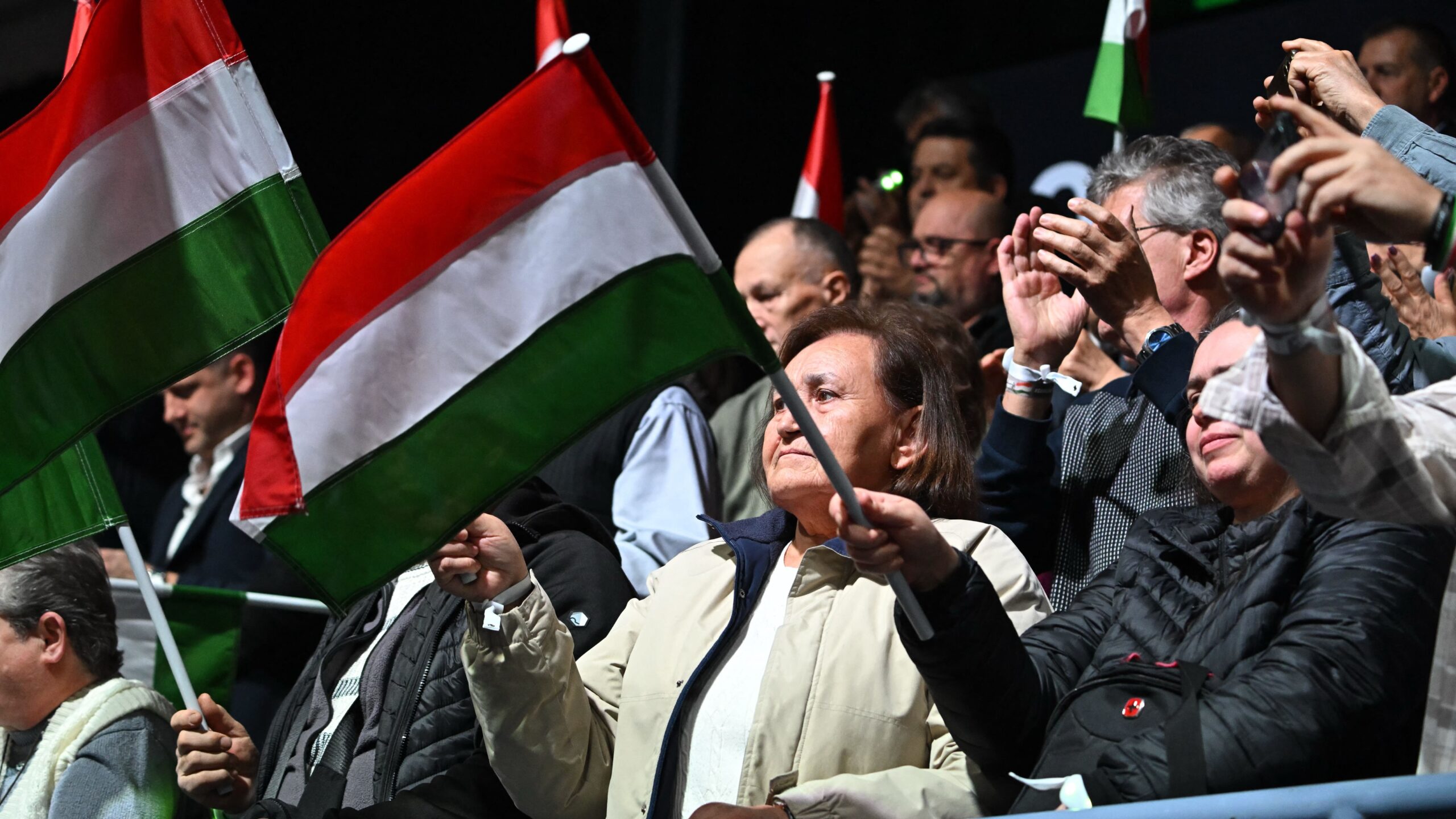 Supporters of Hungarian Prime Minister and chairman of FIDESZ party prime Orban wave Hungarian flags at the local sports hall of Kecskemet, Hungary on December 6, 2025, during a meeting of the Digital Civic Circles.